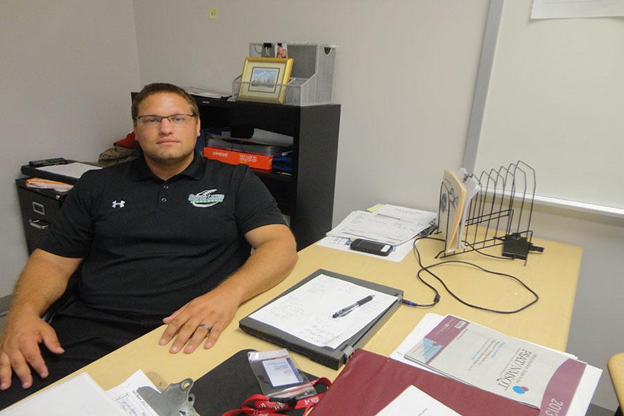 Freshman football coach Stephen Brown sits behind his desk. As well as coaching football, Brown also teaches econmics and history.