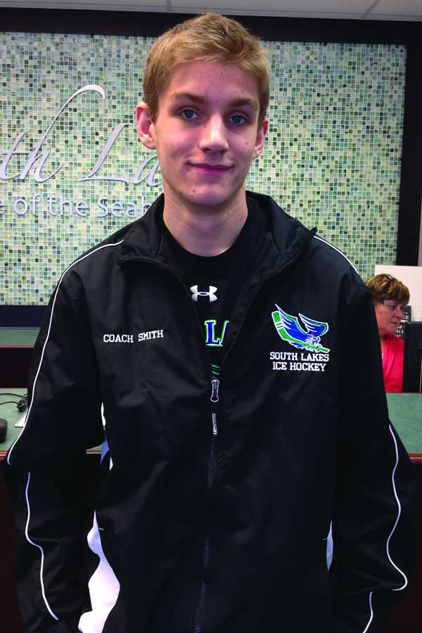 Senior Spencer Smith, a student ice hockey coach, poses in his new coach jacket in the front office.