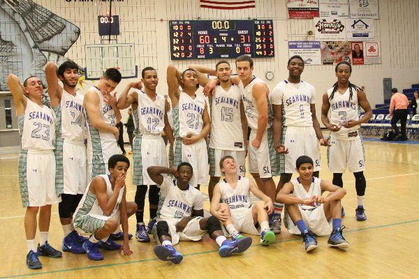 Boys varsity basketball players strike a pose on their home court. 