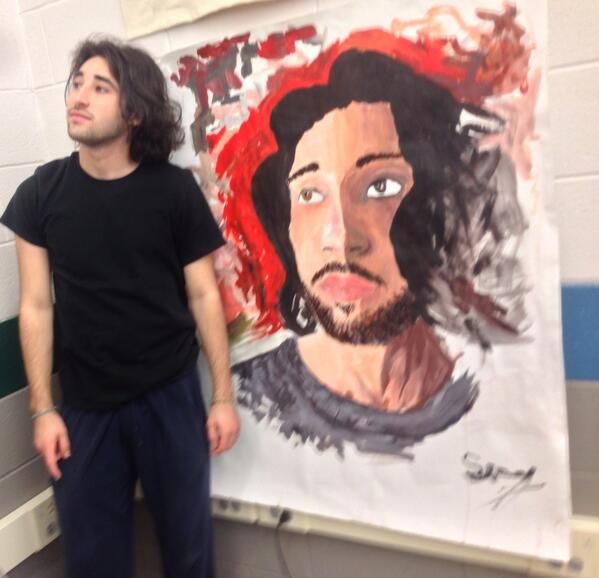 Senior IB art student Sammy Nazam poses next to his self-portrait. 