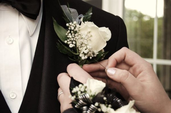 Girl Puts Boutonniere on Her Prom Date, Photo Courtesy of www.www.promdaysecrets.com