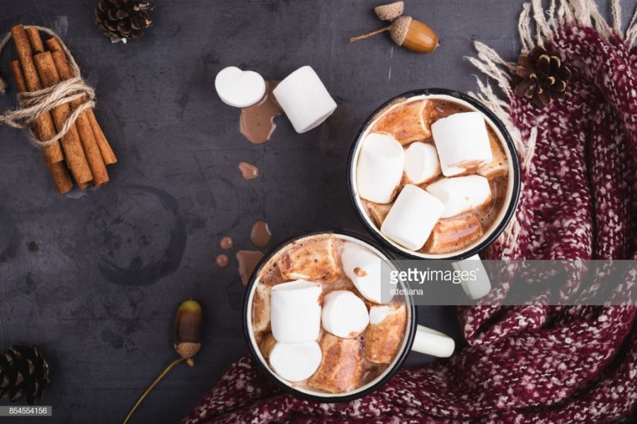 Hot chocolate served in vintage  mugs with marshmallows for two person on table  with woolen scarf wrapped around it; photo taken from Getty Images