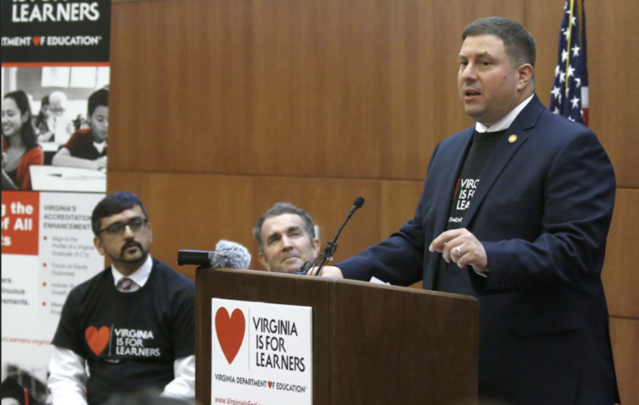 K-12 schools chief takes the podium at an education even in 2019, note Governor Northam in the background - Image via the Richmond Times-Dispatch